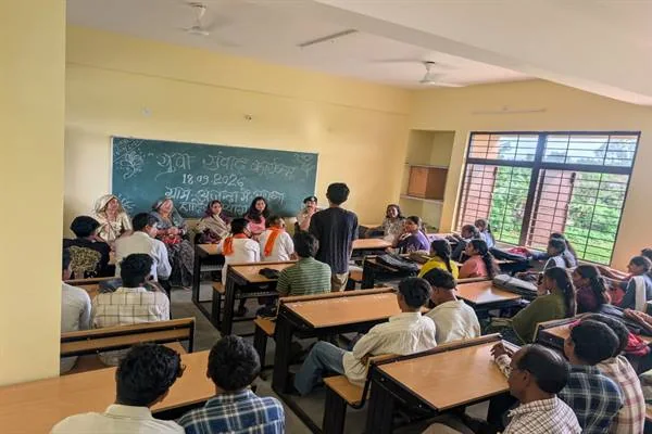कक्षा में डेस्क पर बैठे छात्र-छात्राओं से संवाद करते अधिकारी और अतिथि