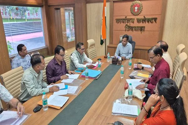 कलेक्टर कार्यालय के सभाकक्ष में मेज के दोनों ओर बैठे अधिकारी दस्तावेजों के साथ बैठक करते हुए
