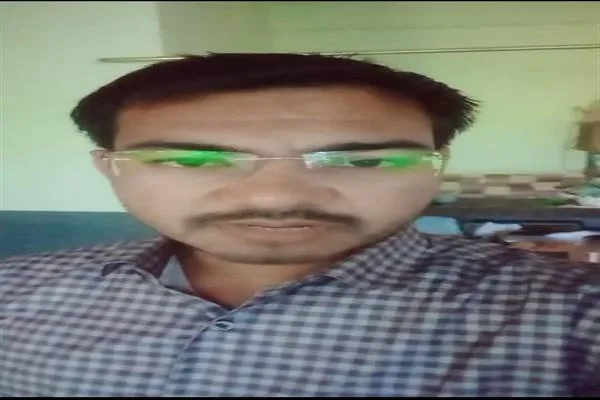 चश्मा और चेकदार कमीज पहने एक युवक का सामने से लिया गया चित्र