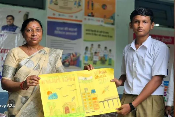 एक महिला और स्कूल यूनिफॉर्म पहना छात्र हाथों में रंगीन चित्र पकड़े खड़े हैं